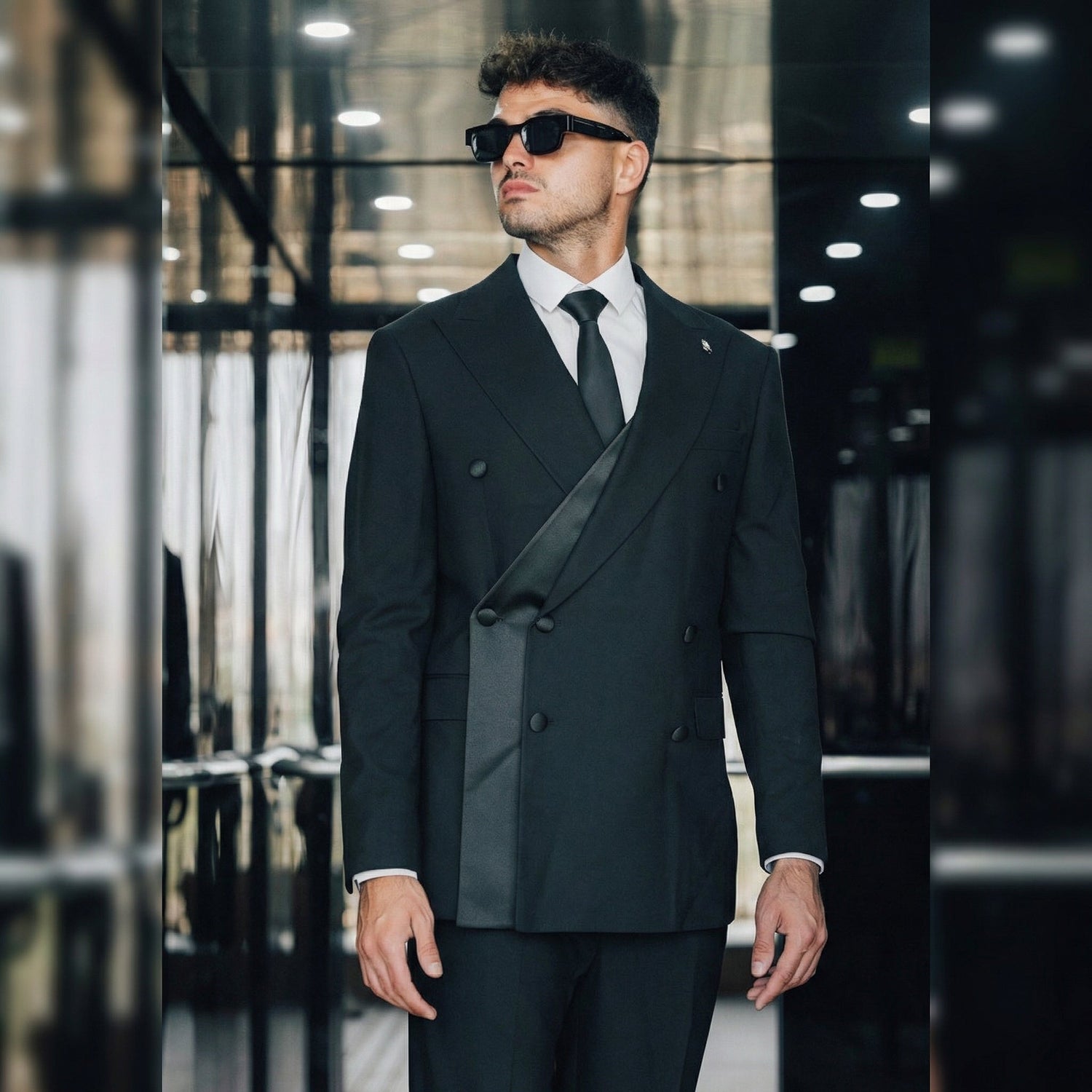 Model wearing a modern fit black Italian wool suit in an upscale city setting